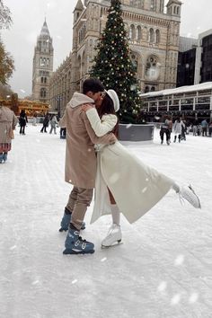 a man and woman are kissing in front of a christmas tree on the ice rink