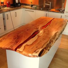 a kitchen counter made out of wood with white cabinets and counters in the back ground