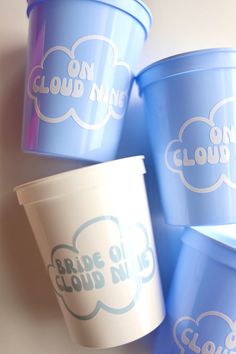 four blue cups with white clouds on the lids are sitting next to each other in front of a wall