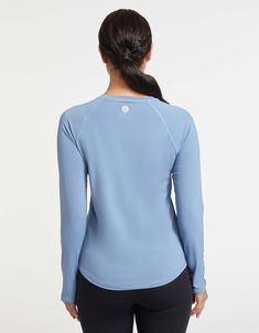 the back view of a woman wearing a light blue shirt and black leggings