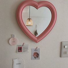 a heart shaped mirror hanging on the wall next to a light switch and other items