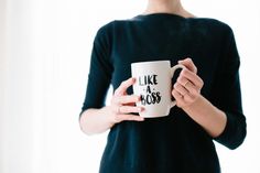 a woman holding a coffee mug with the words like a boss on it