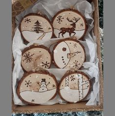 four decorated cookies in a box on top of a table next to a christmas tree