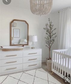 a baby's room with white furniture and a chandelier hanging from the ceiling