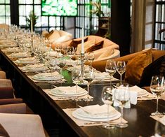 a long table is set with place settings and empty wine glasses for dinner guests to enjoy