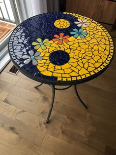 a mosaic table sitting on top of a hard wood floor next to a sliding glass door