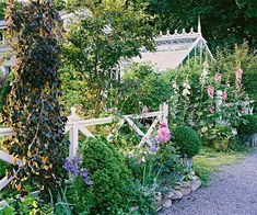 a garden filled with lots of flowers next to a white fence