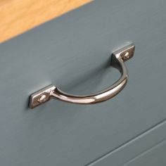 a close up of a metal handle on a gray cabinet with wood floors in the background