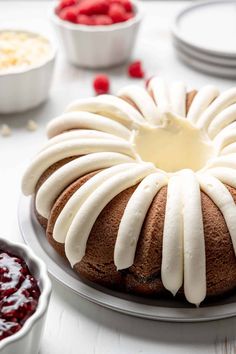 a bundt cake with icing on it sitting on a plate next to other desserts