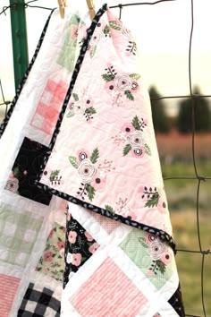 two quilts hanging on a fence with grass in the background