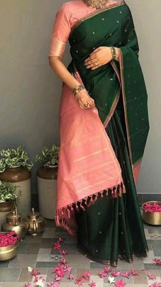 a woman in a green and pink sari with flowers on the ground behind her