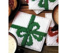 three coasters with green and red designs on them next to two cups of coffee