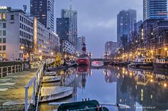 boats are parked along the water in front of some tall buildings and skyscrapers at night