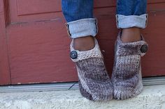 the legs of a person wearing slippers with buttons on them, standing in front of a red door