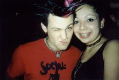 a young man and woman posing for a photo in front of a dark background, with hair on top of their heads