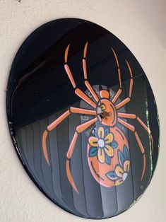 a clock with a spider painted on it's face is hanging on the wall