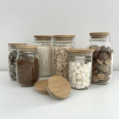 there are many jars with different types of food in them on the table and one has a wooden lid