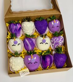 a box filled with purple and white chocolate covered strawberries