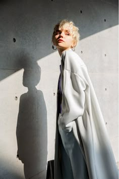 a woman standing in front of a wall with her shadow on the wall behind her