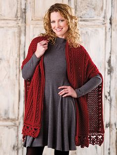 a woman wearing a red knitted shawl and black tights standing in front of a white door