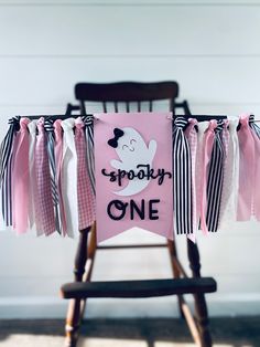 a pink and black birthday banner hanging from a wooden chair