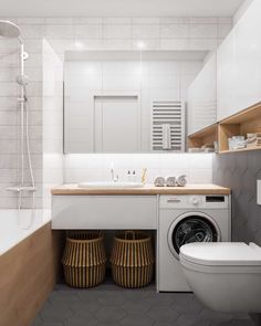 a washer and dryer in a bathroom with white tiles on the walls, along with two baskets