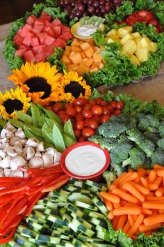 many different types of vegetables are arranged on a table with fruit and veggies