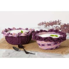 two crocheted bowls with flowers and leaves on the side, one is filled with yogurt