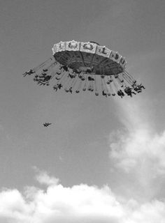 an amusement park ride in the sky with people riding on it's sides and flying around