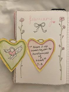 two heart shaped cookies sitting on top of a white paper covered book with words written in it