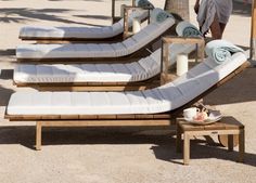 the woman is walking by some lounge chairs on the beach with palm trees in the background