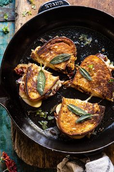 four pieces of grilled meat in a skillet on a wooden table next to flowers