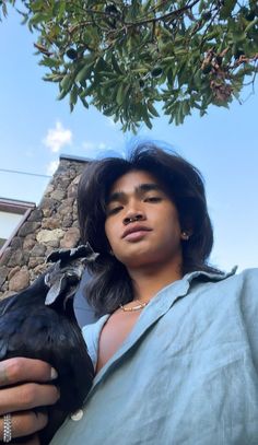 a woman holding a black bird under a tree