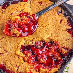 a close up of a skillet cake with cherries on it and a spoon