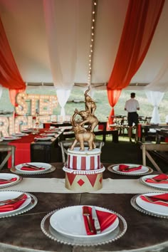 a circus themed table setting with red and white plates, napkins and silverware