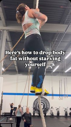 a woman standing on top of a rope in the middle of a crossfit gym