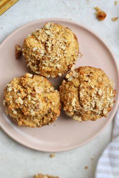 three muffins are on a pink plate next to some oatmeal