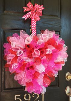 a pink and red wreath hanging on a door with the number 592 written on it