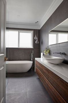 a bathroom with a tub, sink and large mirror on the wall next to it