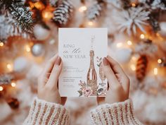 two hands holding up a new year's card in front of a christmas tree