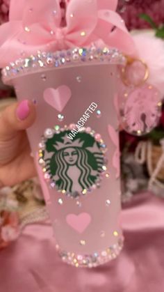 a pink starbucks cup with hearts on it and a bow in the middle is being held by a woman