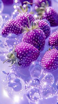 some purple strawberries are laying on top of each other with bubbles around them and water droplets surrounding them