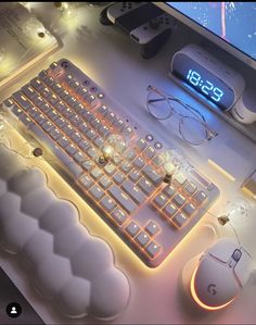 an illuminated keyboard and mouse on a desk next to a computer monitor with the time displayed