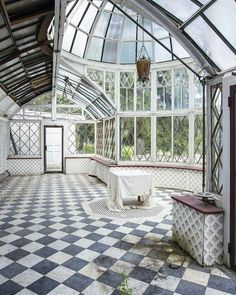 an empty room with checkered flooring and large glass windows on the ceiling, along with a bench in the center