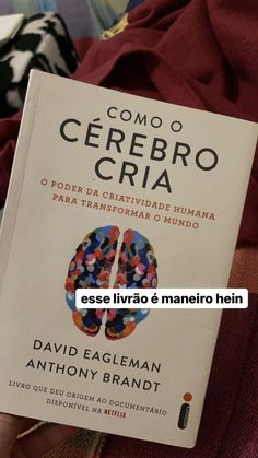 a person holding up a book in their hand with the title com o cerebro cria