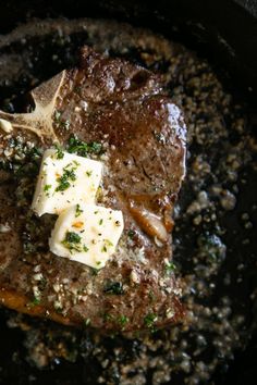 a piece of meat in a skillet with cheese and herbs on top, ready to be cooked