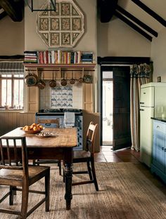 a table and chairs in a room with exposed beams on the ceiling, bookshelf above