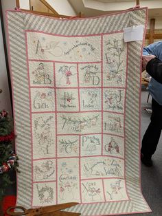 a woman holding up a quilt with words on it