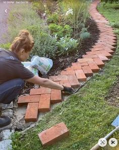 a woman is laying bricks on the ground