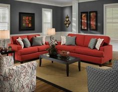 a living room filled with red couches and pillows on top of a wooden floor